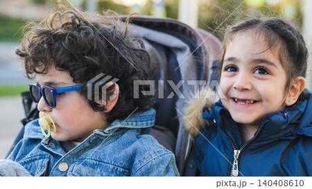 Siblings enjoying an outdoor walk, little boy with pacifier and sunglasses in stroller 140408610
