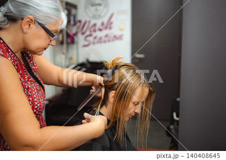 Hairdresser cutting woman's hair in a salon 140408645