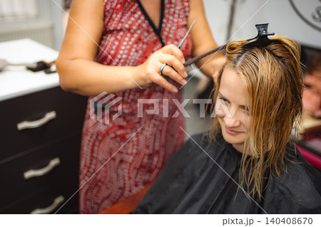 Hairdresser styling woman's wet hair in salon 140408670