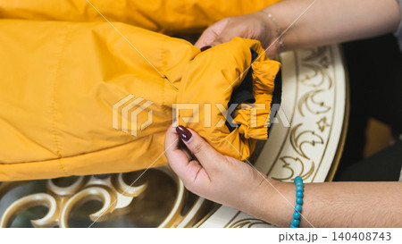 Hands checking sleeve cuff of yellow winter jacket before cold weather 140408743