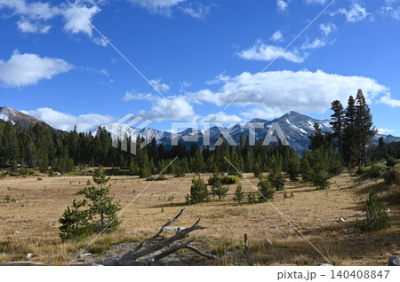 Scenic subalpine lake and pine forest below rugged mountain peaks with white clouds. Scenic subalpine lake and pine forest below rugged mountain peaks with white clouds. 140408847