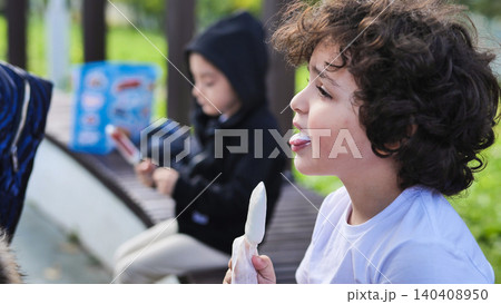 Curious child with curly hair eating a sweet treat outdoors on a sunny day Curious child with curly hair eating a sweet treat outdoors on a sunny day 140408950