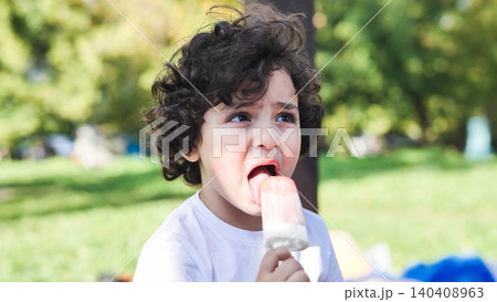 Young child enjoying a refreshing popsicle during a hot summer day in a park Young child enjoying a refreshing popsicle during a hot summer day in a park 140408963