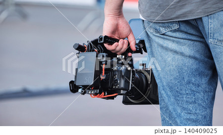Man holding digital cinema camera with video rig, filmmaking equipment in hand Man holding digital cinema camera with video rig, filmmaking equipment in hand 140409025
