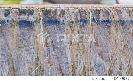 Close up of a waterfall flowing over a stone ledge creating a serene abstract background. 140409087