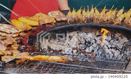 Chef grilling fish, prawns and meat skewers on barbecue at street food market Chef grilling fish, prawns and meat skewers on barbecue at street food market 140409220