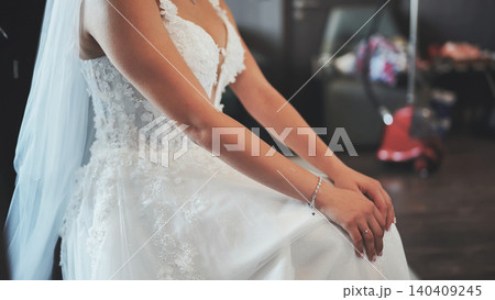 Bride in elegant white lace wedding dress sits calmly before the ceremony. Bride in elegant white lace wedding dress sits calmly before the ceremony. 140409245