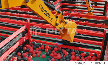 Mechanical arm of excavator toy picking up red and black balls during sports day Mechanical arm of excavator toy picking up red and black balls during sports day 140409281