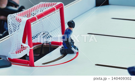 Close up of a blue goalie figure in a tabletop hockey game defending the goal. Close up of a blue goalie figure in a tabletop hockey game defending the goal. 140409302