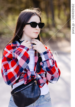Young stylish woman adjusting headphones while listening to music outdoors Young stylish woman adjusting headphones while listening to music outdoors 140409482