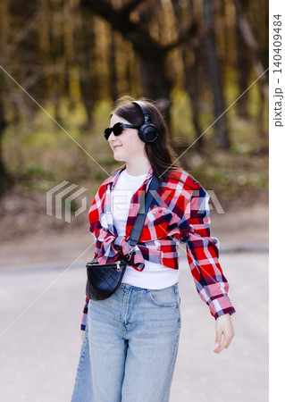 Young stylish girl enjoying music while roller skating in park Young stylish girl enjoying music while roller skating in park 140409484