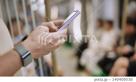 Hands holding smartphone, connecting and communicating on subway train 140409530