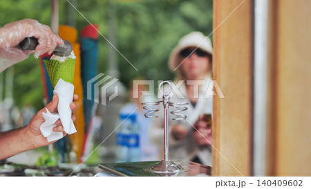 Street vendor serving ice cream to customer in green cone 140409602