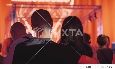 Couple embracing while watching a live concert with vibrant stage lights Couple embracing while watching a live concert with vibrant stage lights 140409735