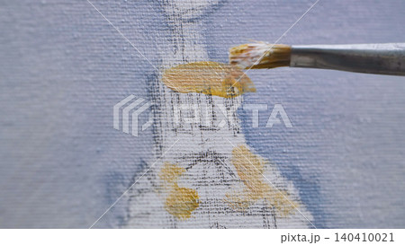 Artist painting with brush on canvas, adding yellow ochre color to artwork Artist painting with brush on canvas, adding yellow ochre color to artwork 140410021