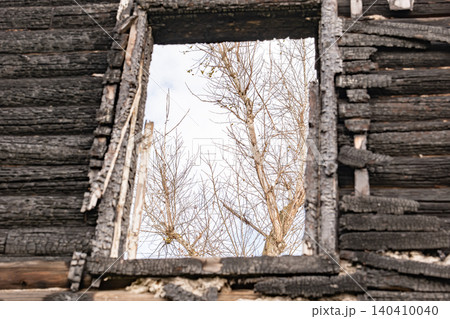 Burnt house window frame showing destruction and the bare trees of nature changing Burnt house window frame showing destruction and the bare trees of nature changing 140410040