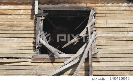 Charred window frame and broken pieces of wood on a damaged house after a fire 140410046