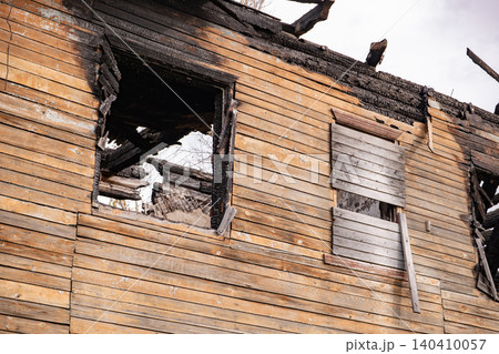 Burnt building exterior with charred wood planks and broken windows from a house fire 140410057