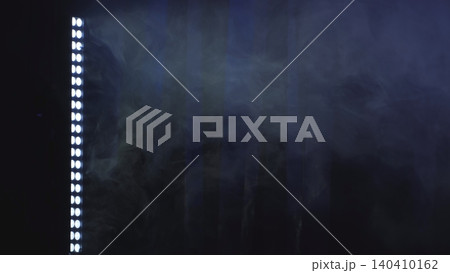 Bright stage lights illuminating fog and smoke streaks at a dark show event 140410162