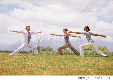 Group, women and yoga instructor in warrior pose outdoor for healthy body, exercise or fitness. Teacher, virabhadrasana and people in nature for balance, stretching and holistic practice for wellness 140410223