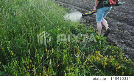 Farmer applying herbicide to control weeds in a cultivated field, using a hand held sprayer to protect crops and promote growth Farmer applying herbicide to control weeds in a cultivated field, using a hand held sprayer to protect crops and promote growth 140410334