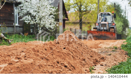 Bulldozer working on rural village road clearing soil for new infrastructure Bulldozer working on rural village road clearing soil for new infrastructure 140410444