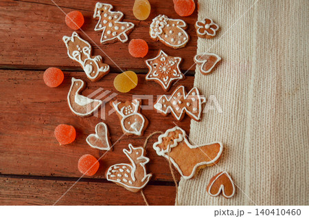 Decorated gingerbread pieces with icing details are spread across textured wood. Bright details create cheerful holiday atmosphere. Decorated gingerbread pieces with icing details are spread across textured wood. Bright details create cheerful holiday atmosphere. 140410460