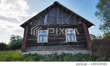Old weathered wooden house in a rural field under a cloudy sky 140410481