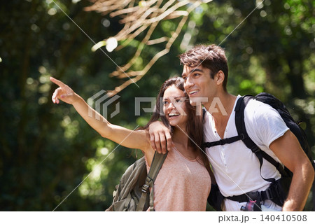 Couple, point and smile for hiking in jungle with sign for thinking, holiday and happy on path. Man, woman and bag for trekking, direction and search in rainforest with ideas at location in Colombia 140410508