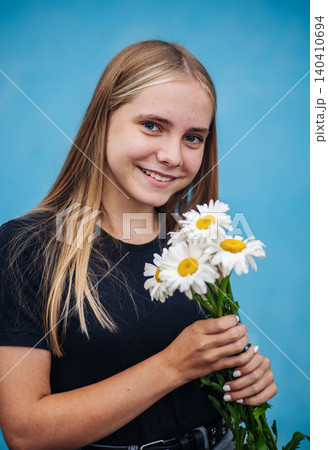 Blonde teenage girl smiling, holding a bouquet of fresh white daisies Blonde teenage girl smiling, holding a bouquet of fresh white daisies 140410694