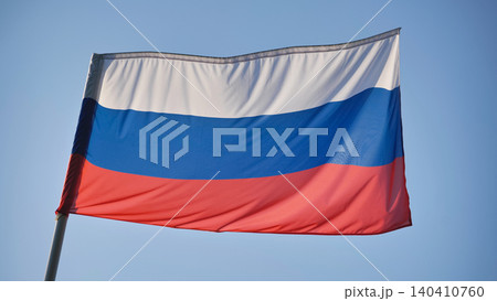 Russian tricolor flag with white, blue, and red stripes flapping in the wind on a sunny day 140410760