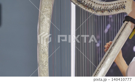 Harpist performing classical music with elegant details, playing strings during a show Harpist performing classical music with elegant details, playing strings during a show 140410777