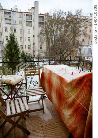 Snowy apartment balcony with chairs and table 140410808