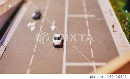 Miniature cars driving on a road diorama with pedestrian and streetlights Miniature cars driving on a road diorama with pedestrian and streetlights 140410841