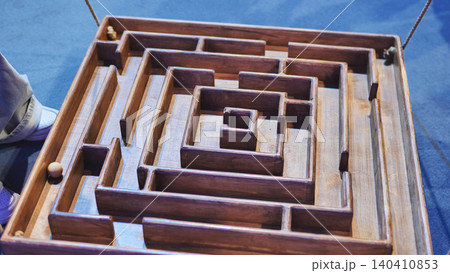 Wooden maze game challenging players to guide a ball through a complex labyrinth Wooden maze game challenging players to guide a ball through a complex labyrinth 140410853