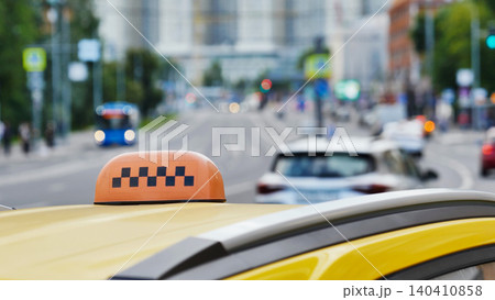 Yellow taxi car roof sign waiting in urban traffic on blurred city street Yellow taxi car roof sign waiting in urban traffic on blurred city street 140410858