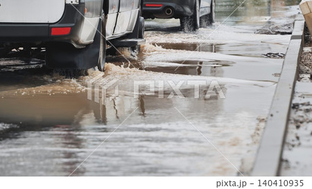 Cars driving on flooded street splashing muddy water after heavy rainfall Cars driving on flooded street splashing muddy water after heavy rainfall 140410935