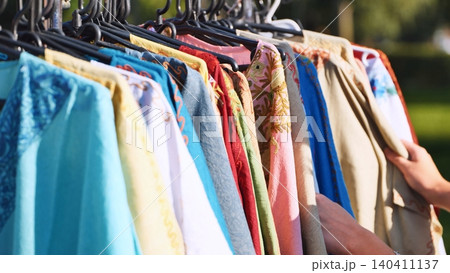 Hands browsing a rack of vibrant Indian ethnic clothing at a cultural festival Hands browsing a rack of vibrant Indian ethnic clothing at a cultural festival 140411137