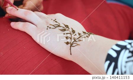 Applying traditional henna body art design on hand during India Day festival in Moscow Applying traditional henna body art design on hand during India Day festival in Moscow 140411153