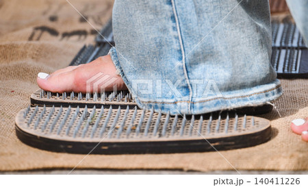 Woman practicing yoga and stepping on sadhu board with nails in India Woman practicing yoga and stepping on sadhu board with nails in India 140411226