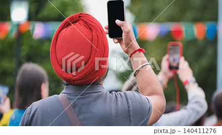 Sikh man in red turban filming celebration with smartphone at India Day in Moscow Sikh man in red turban filming celebration with smartphone at India Day in Moscow 140411276