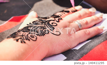 Applying traditional henna tattoo art onto a woman's hand during an Indian festival Applying traditional henna tattoo art onto a woman's hand during an Indian festival 140411295