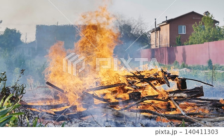 Backyard fire burning wood and debris in residential area. Intense flames and smoke rising Backyard fire burning wood and debris in residential area. Intense flames and smoke rising 140411303