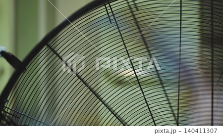 Electric fan grille cooling air in motion, blurred green background Electric fan grille cooling air in motion, blurred green background 140411307