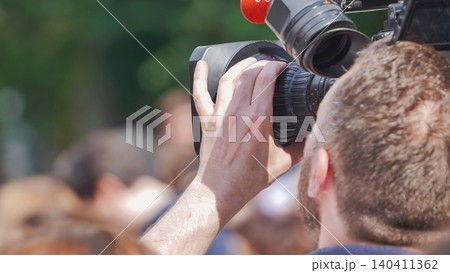 Cameraman filming crowd with professional video camera for live broadcast news Cameraman filming crowd with professional video camera for live broadcast news 140411362