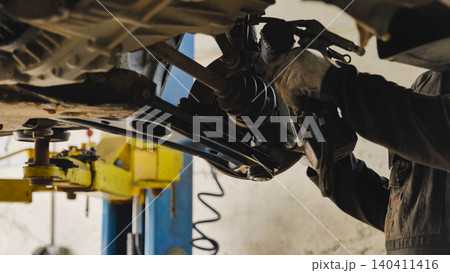 Mechanic repairing car chassis lifted on a hydraulic ramp 140411416