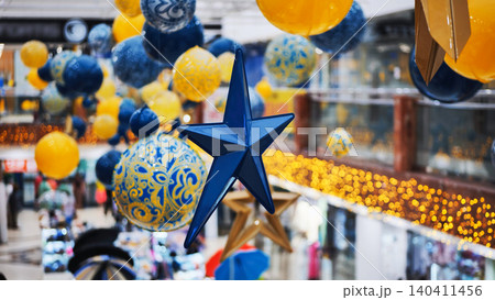 Blue christmas star hanging in a shopping mall with yellow and blue decorations Blue christmas star hanging in a shopping mall with yellow and blue decorations 140411456