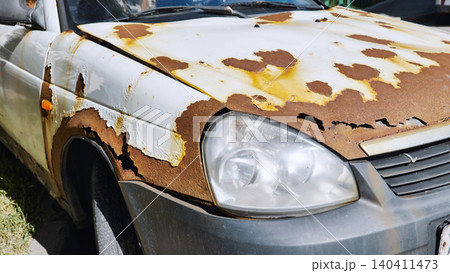 Rusty old white car parked on the street is decaying 140411473