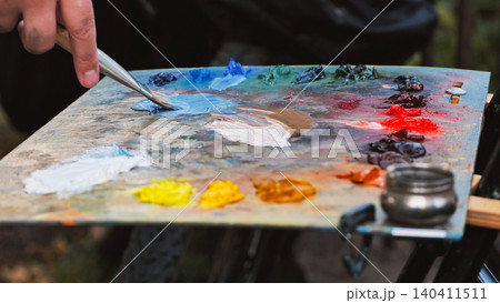 Painter mixing oil colors on palette with brush in art studio Painter mixing oil colors on palette with brush in art studio 140411511
