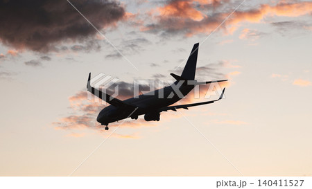 Passenger airplane landing at sunset with cloudy sky Passenger airplane landing at sunset with cloudy sky 140411527